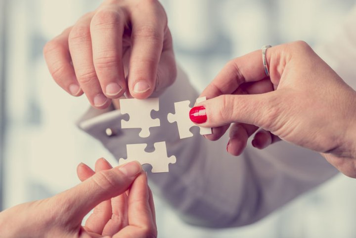 Kombinationsleistung Pflegeversicherung - Nahaufnahme: drei weiße Puzzleteile werden von drei Personen mit ihren Händen aneinander gehalten.