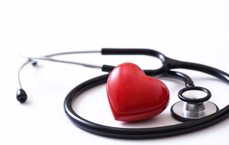 Ein Stethoskop und ein rotes Herz liegen auf einer weißen Oberfläche.