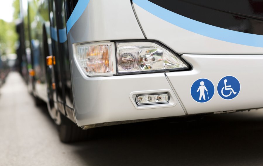Eine Nahaufnahme der Front eines Fernbusses. Neben dem Scheinwerfer sind zwei blaue, runde Aufkleber mit einem Rollstuhlfahrer und einem Menschen mit Gehstock als Kennzeichung für die Beförderung von Personen mit einer Gehbehinderung angebracht.
