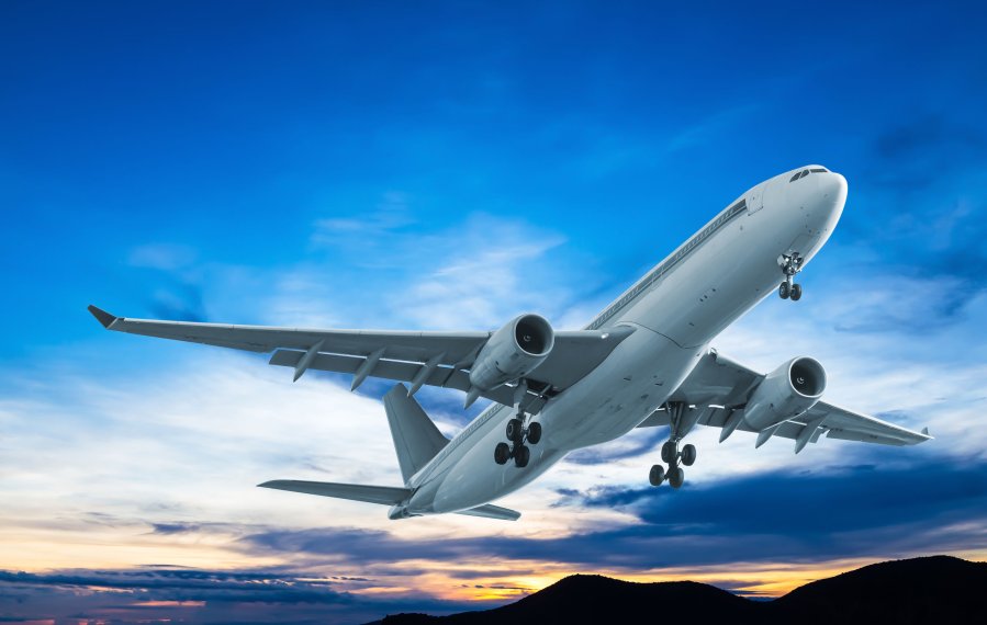 Ein Flugzeug ist gerade gestartet. Im Hintergrund die Abenddämmerung.