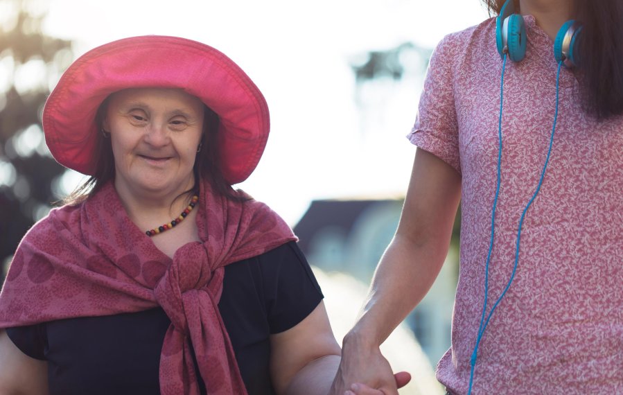 Zwei Frauen halten sich an der Hand und gehen spazieren. Es ist Sommer. 