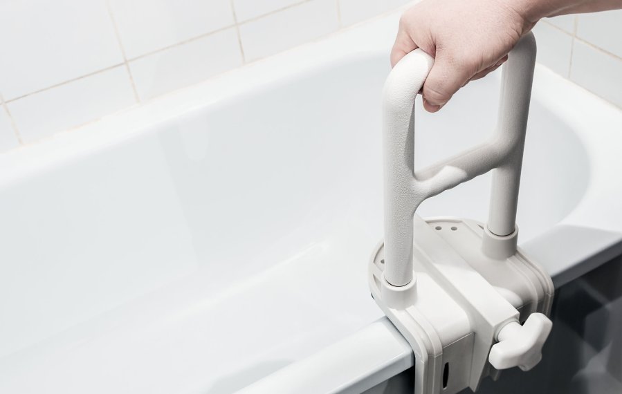 Ein Haltegriff, der an die Badewanne montiert wurde. Eine Hand umfasst den Griff.