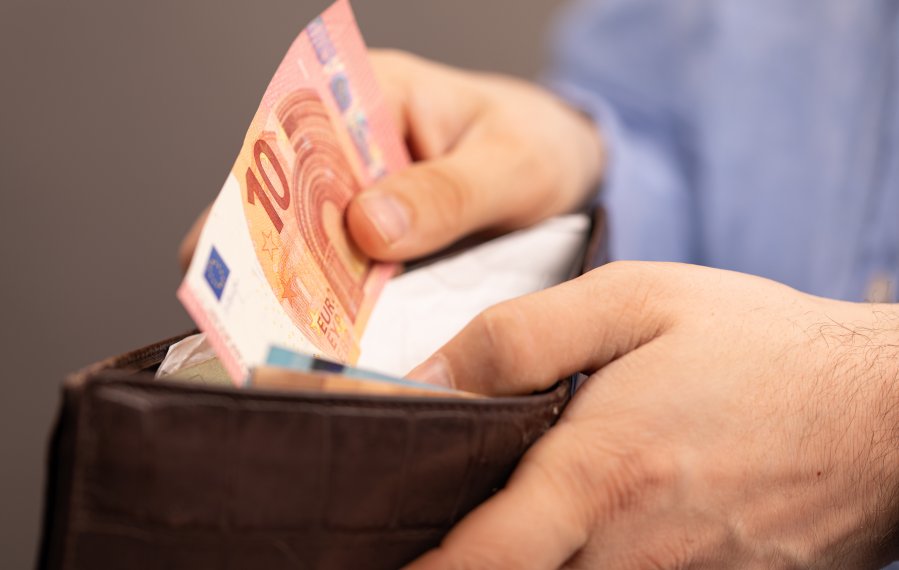Übergangsgeld - Hände öffnen einen Ledergeldbeutel. In dem Geldbeutel befinden sich Euro-Geldscheine.